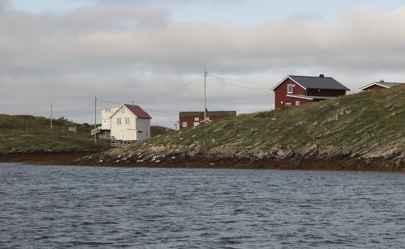 White house and red barn on a green coastal headland over dark water