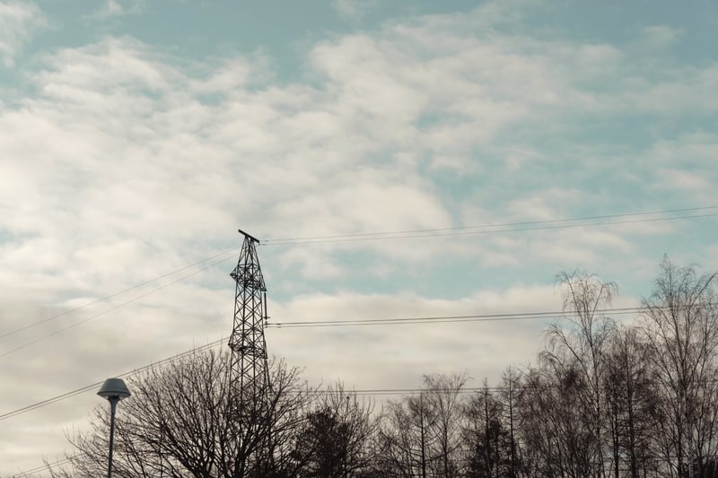 Power pylon and lines against a winter sky, arena dome in the distance
