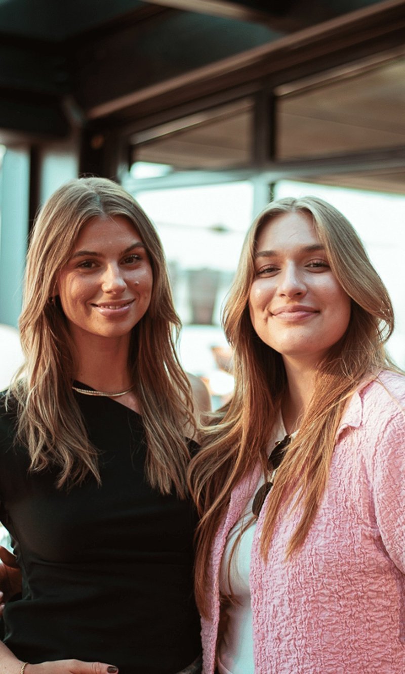 Two Vainu colleagues smiling together on a rooftop terrace in golden evening light